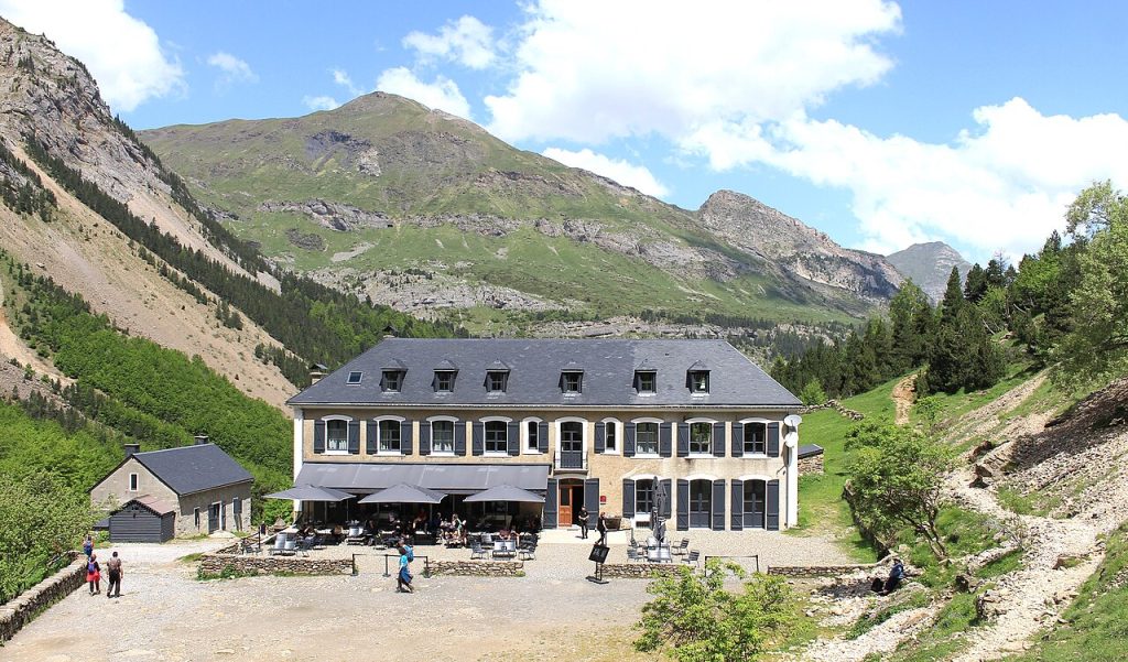 קרקס גווארני - אכסניית הרים כפרית גדולה בת שתי קומות בסגנון צרפתי מסורתי, עם גג
אפור-כחלחל וחלונות בעלי תריסים כהים. בחזית הבניין טרסת ישיבה חיצונית עם
שולחנות ומטריות אפורות ומבקרים יושבים. הבניין שוכן בעמק הרים ירוק בפירנאים,
מוקף בצמחייה ועצי אורן, עם רכס הרים גבוה ומרשים ברקע תחת שמיים כחולים
עם עננים לבנים.